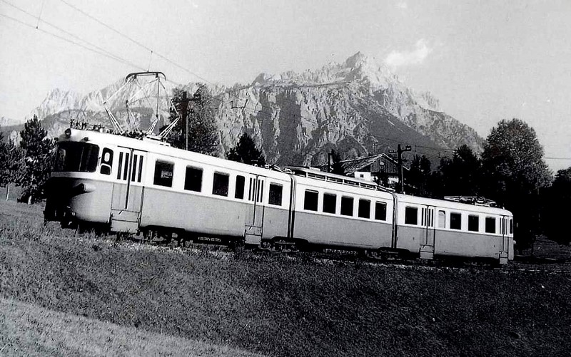 15b) Elettrotreno 007 SFD in transito verso Dobbiaco in località Majon a Cortina. Sullo sfondo il monte Faloria primi anni sessanta..jpg