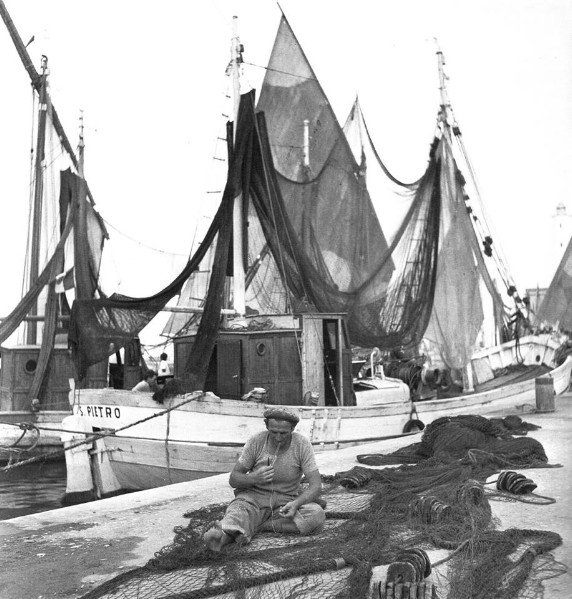 278c-Porto Garibaldi,  lungo il porto-canale qualche anno fa, tra le vele dei barchetti, le reti da pesca appese agli alberi delle barche, il marinaio che aggiusta la rete..jpg